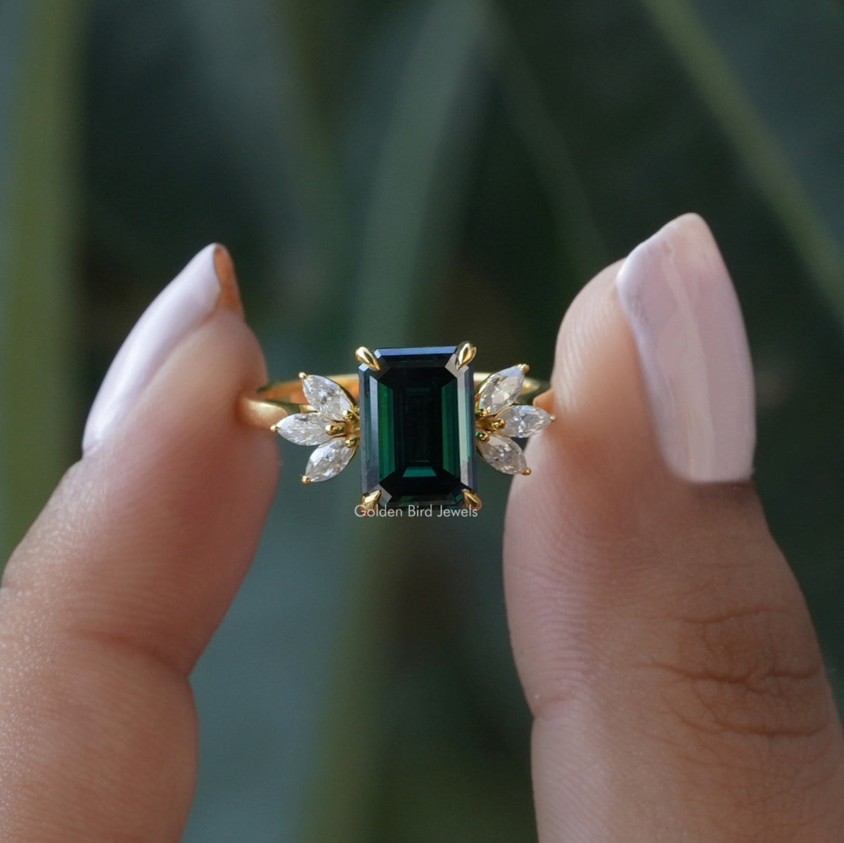 Two fingers holding the Moissanite Emerald Cut Engagement Ring