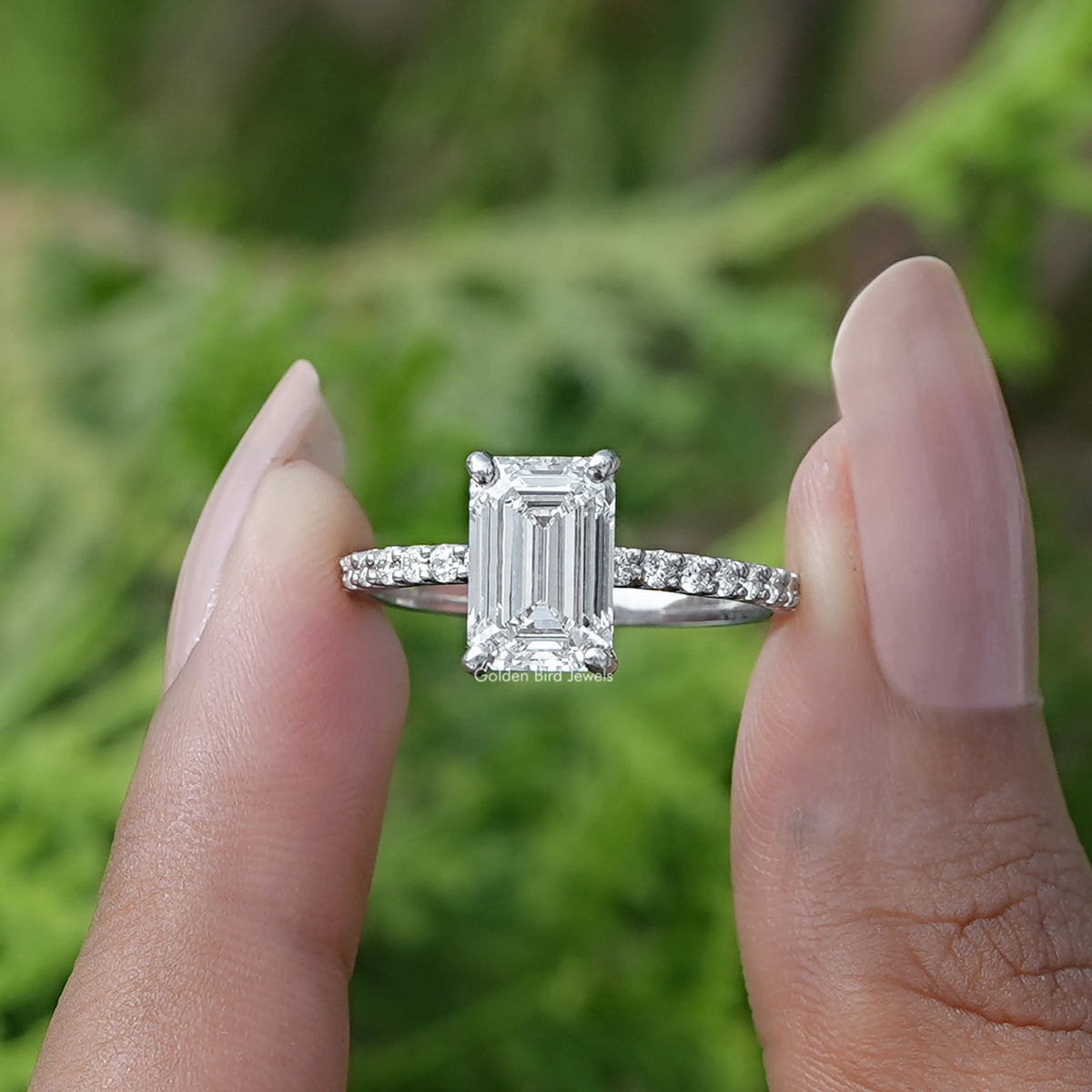 Two fingers holding the Emerald Cut Solitaire Diamond Ring