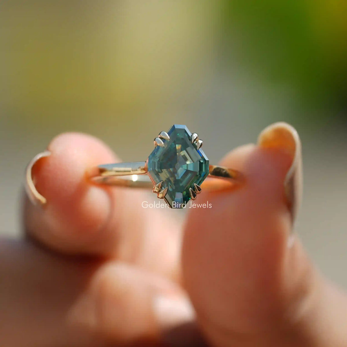 Front View of Blue-Green Fancy Cut Moissanite Solitaire Ring In Two Fingers