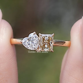 Front view of Radiant And Heart Cut Moissanite Two Stone Ring in two fingers 
