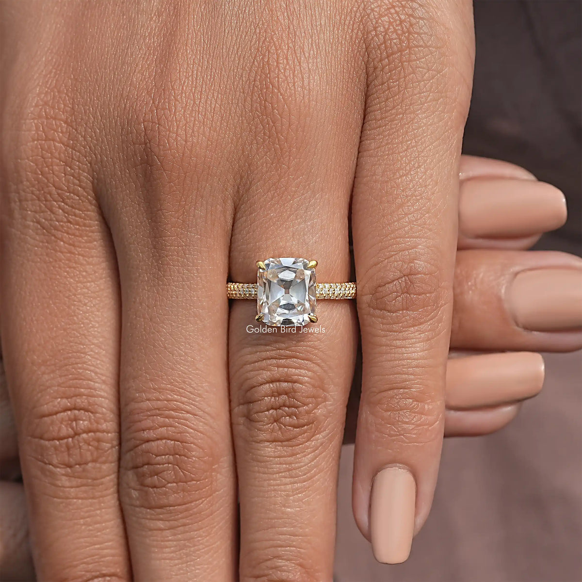 Moissanite solitaire engagement ring on hand; cushion center with pave band