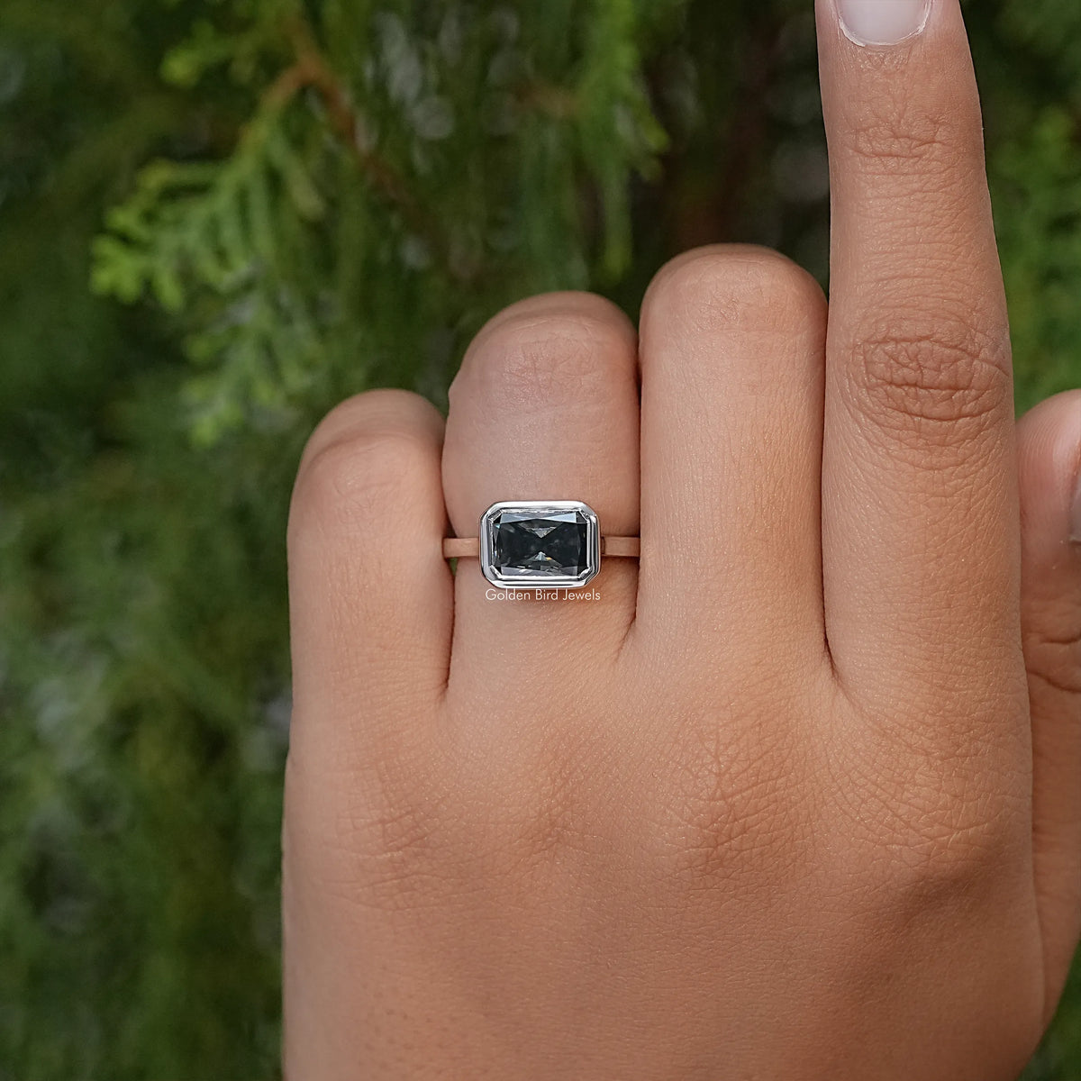 Square gray moissanite solitaire ring on hand with slim silver band and four prongs