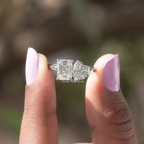 Emerald Cut Moissanite ring holding on two fingers 
