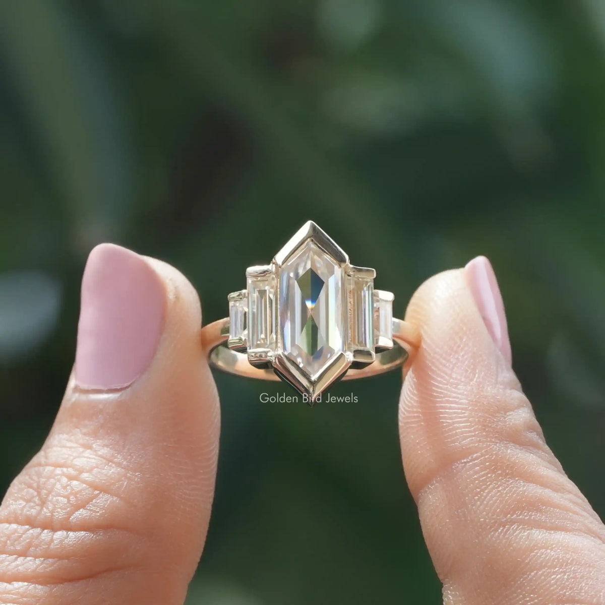 Two fingers holding the Hexagon Cut Moissanite Five Stone Ring