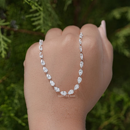 Silver pear-cut diamond tennis necklace held in hand, teardrop stations