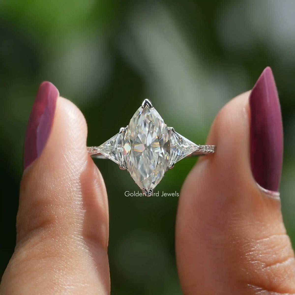Two fingers holding the Marquise And Triangle Cut Hidden Halo Ring