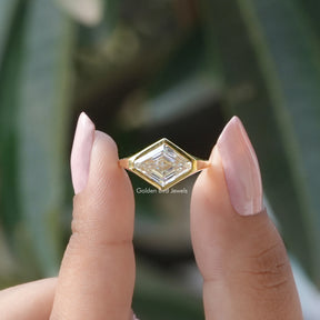 Two fingers holding the Lozenge Cut Moissanite Bezel Set Solitaire Ring