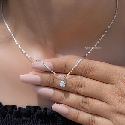 Silver moissanite solitaire pendant with round stone on chain, resting across fingers