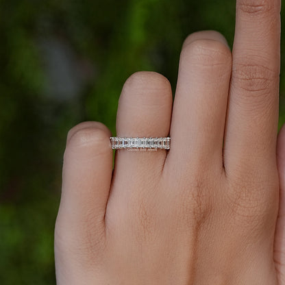 Silver half-eternity baguette-cut ring on finger, straight-on view