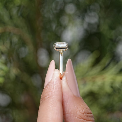 Emerald-cut moissanite bezel setting on a toi et moi ring, silver-tone band.
