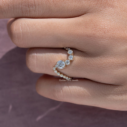 Gold wave wedding band with clustered round stones, close side view on finger