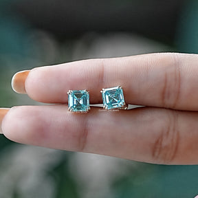 In two finger view of asscher cut moissanite stud earrings 