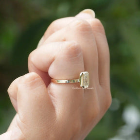 Sparkling emerald cut bezel set moissanite ring displayed on finger