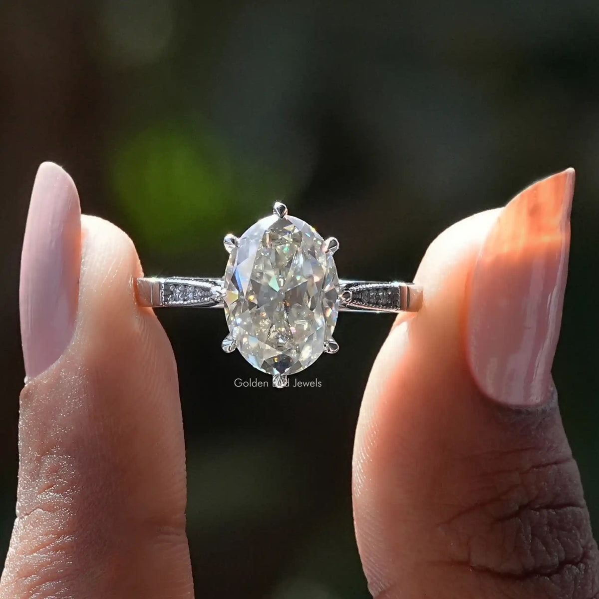 Two fingers holding the Old Mine Oval Cut Accent Stone Moissanite Ring