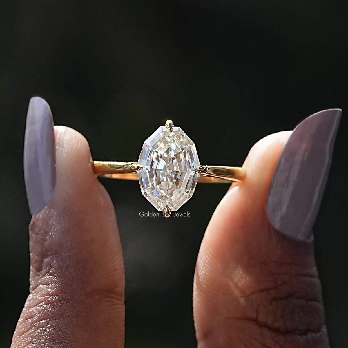 Two fingers holding the Step Cut Oval Hidden Halo Engagement Ring