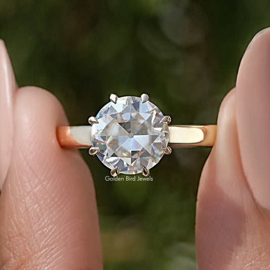 Round moissanite solitaire ring with prong-set center stone and thin gold-toned band