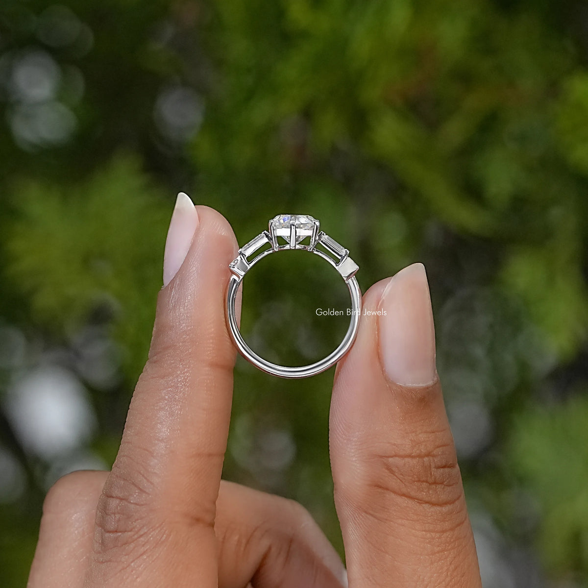 Sterling silver ring shown from the side, with raised round and baguette stones