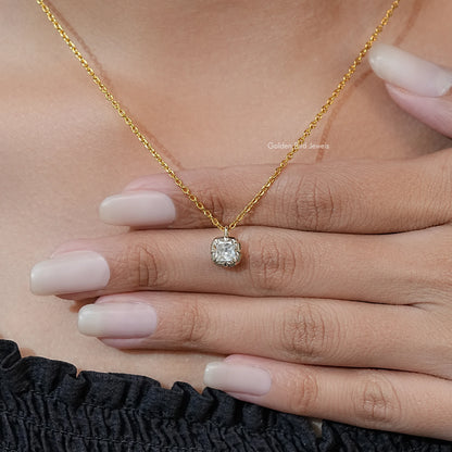 Gold tone moissanite pendant in round prong setting on chain, held in hand