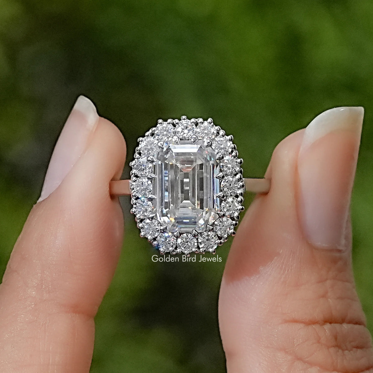Emerald-cut moissanite solitaire ring with a halo of accent stones and a slim silver band
