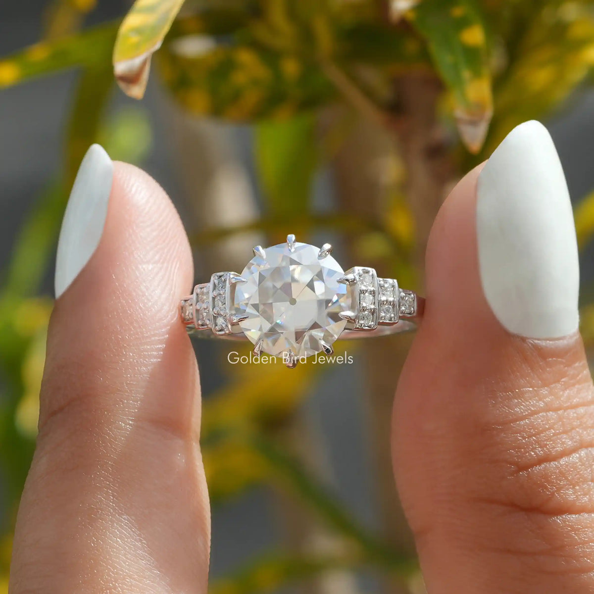 Two fingers holding the Old European Round Cut Moissanite Ring