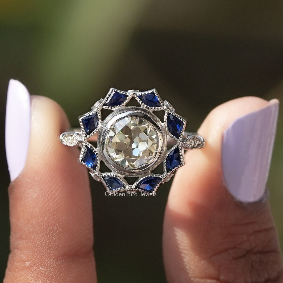 Two fingers holding the Old European Round Cut Bezel Set Moissanite Ring