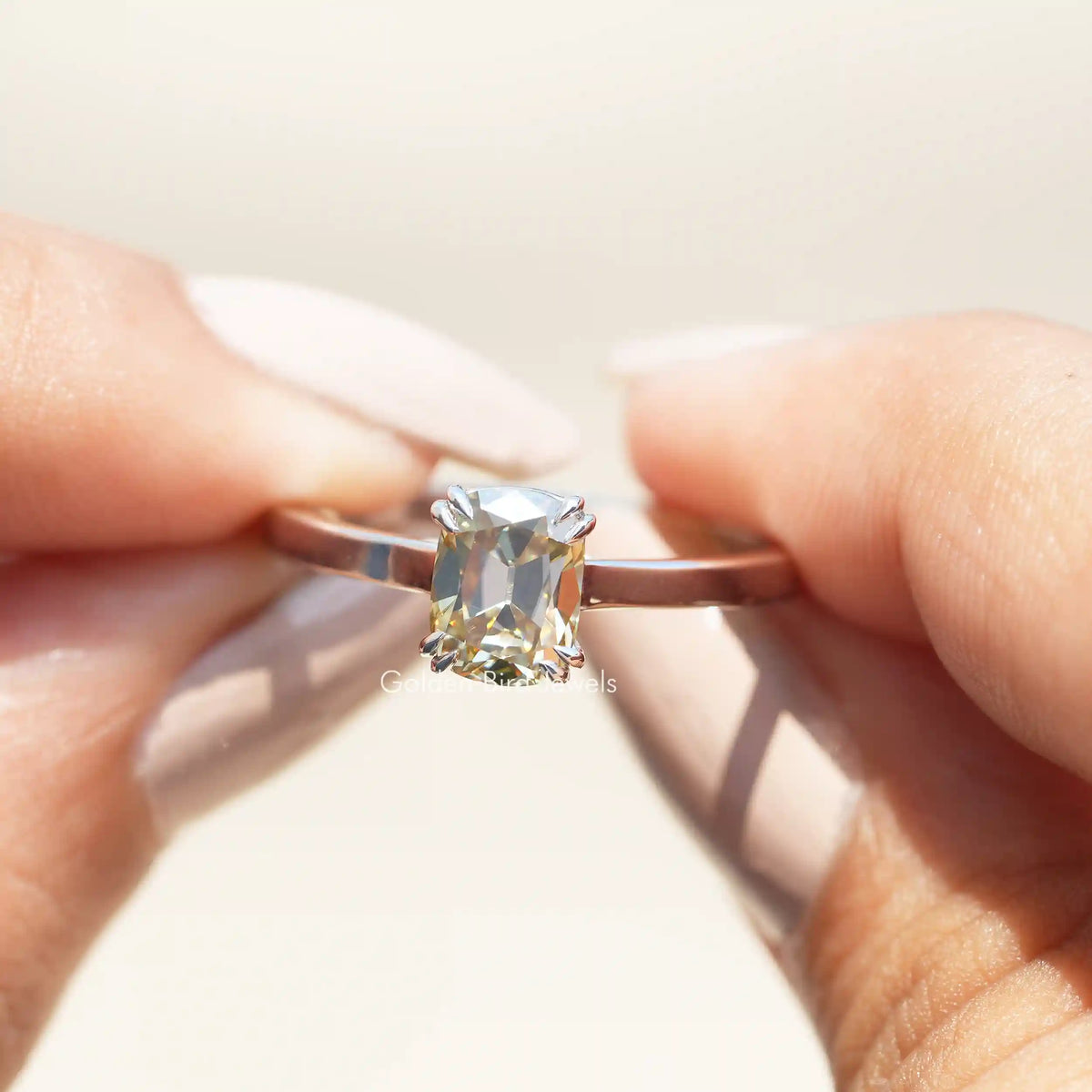 Two fingers holding the Old Mine Cushion Cut Moissanite Solitaire Ring
