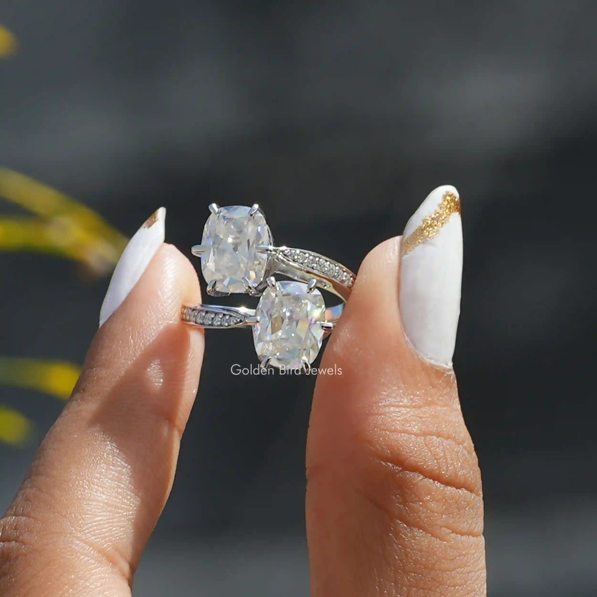 Two fingers holding the Old Mine Cushion Cut Moissanite Ring