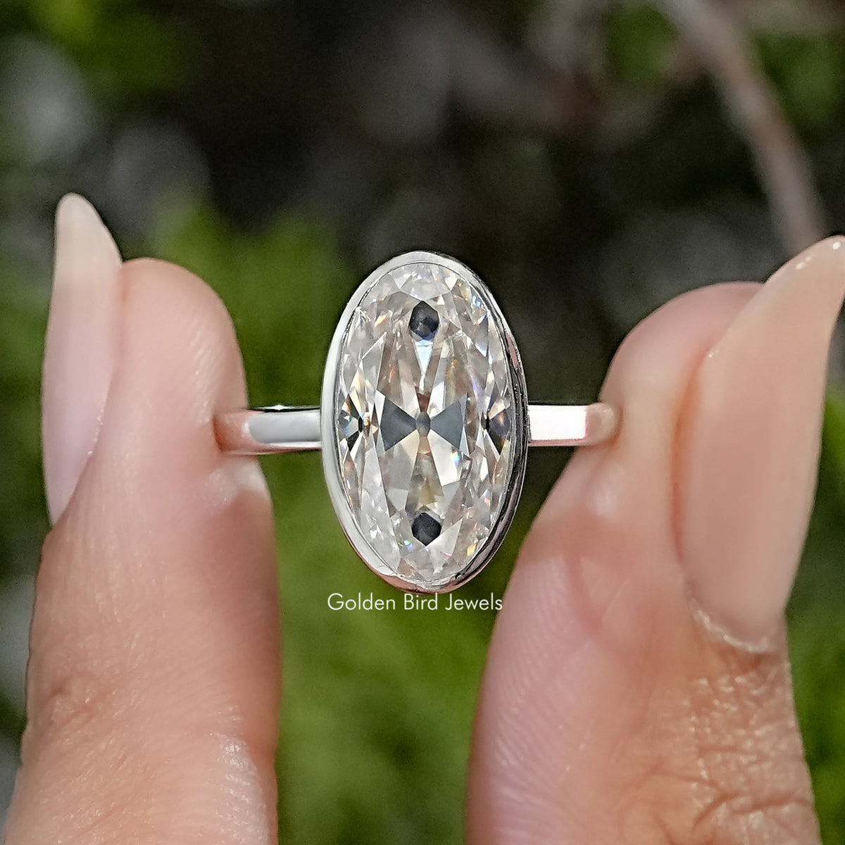 Sterling silver solitaire ring with an elongated oval moissanite in a bezel setting.