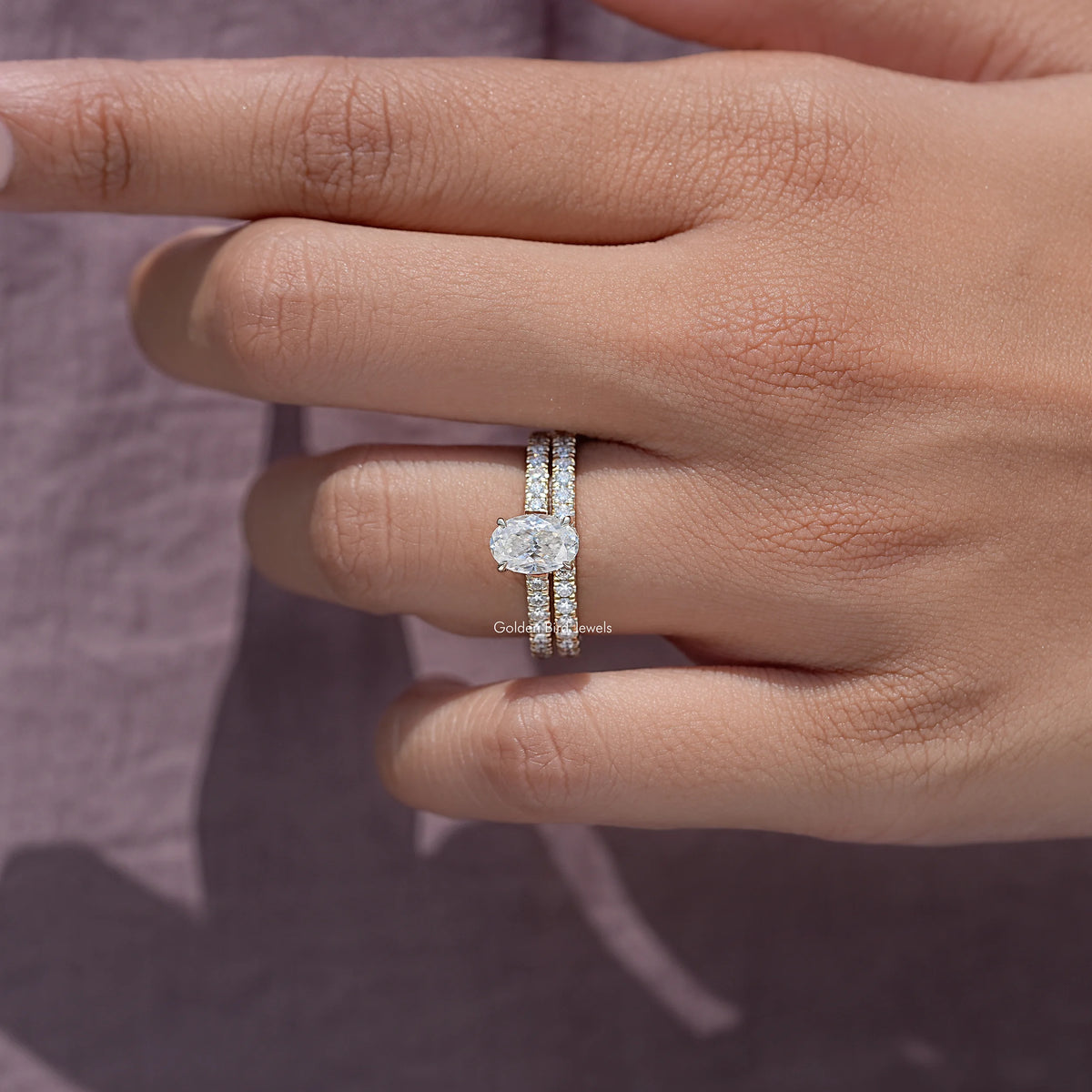 Moissanite wedding ring set with oval center stone and pavé bands on hand