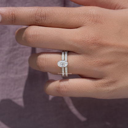 Moissanite wedding ring set with oval center stone and pavé bands on hand