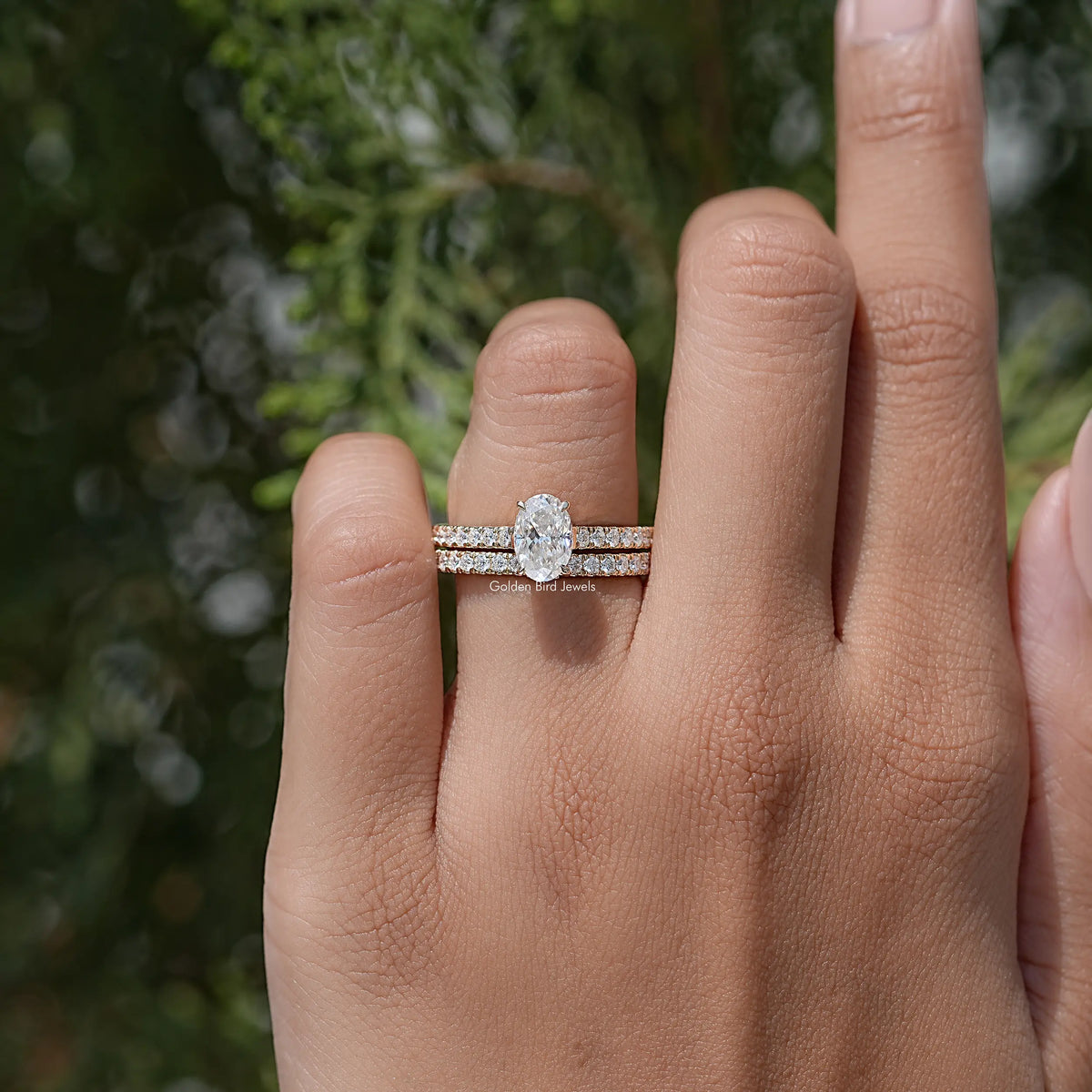 Oval-cut moissanite wedding ring set with pavé bands on a hand