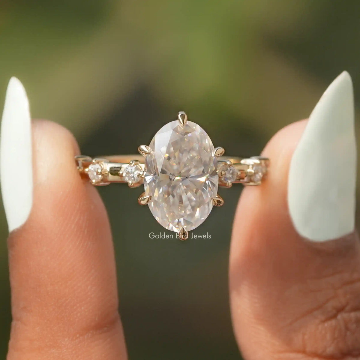Two fingers holding the Oval Cut Moissanite Accent Stone Ring