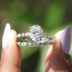 Two fingers holding the Oval Cut Moissanite Bridal Ring Set