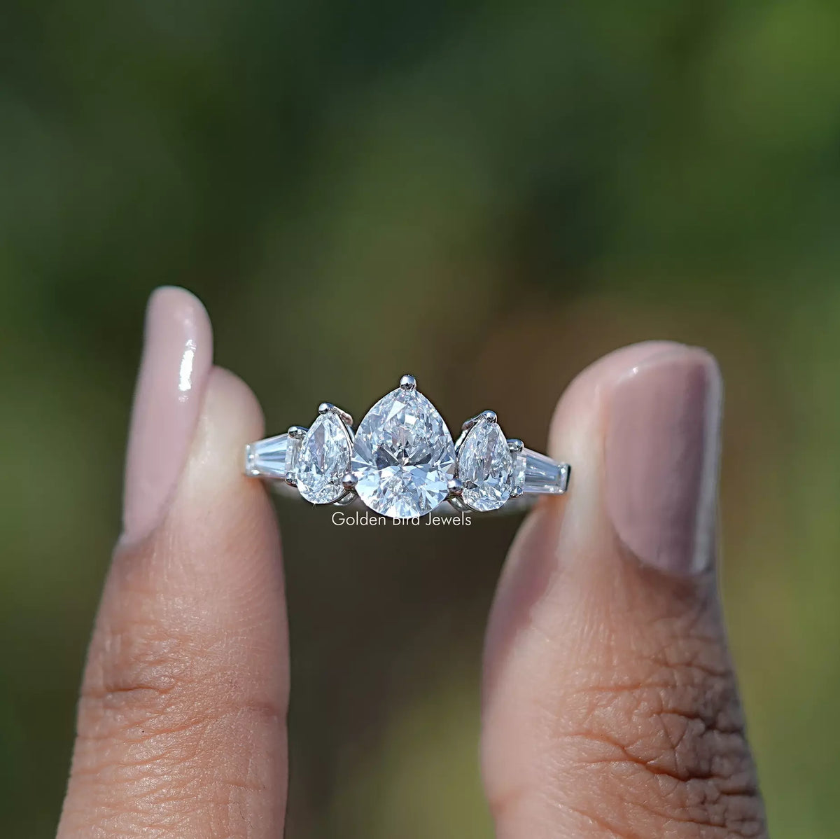 Two fingers holding the Pear Cut Lab Grown Diamond Five Stone Ring