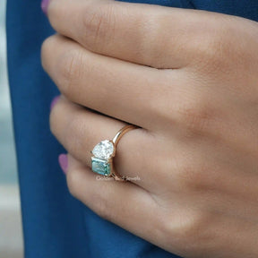 Slightly folded finger side view of pear and emerald cut toi et moi ring