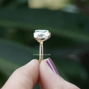 Hold on two finger side view of yellow gold emerald and pear cut ring