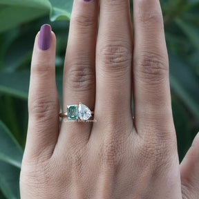 On finger front view of toi et moi pear and emerald cut ring