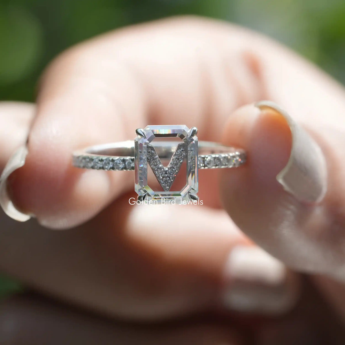 Two fingers holding the Emerald Cut Moissanite Engagement Ring