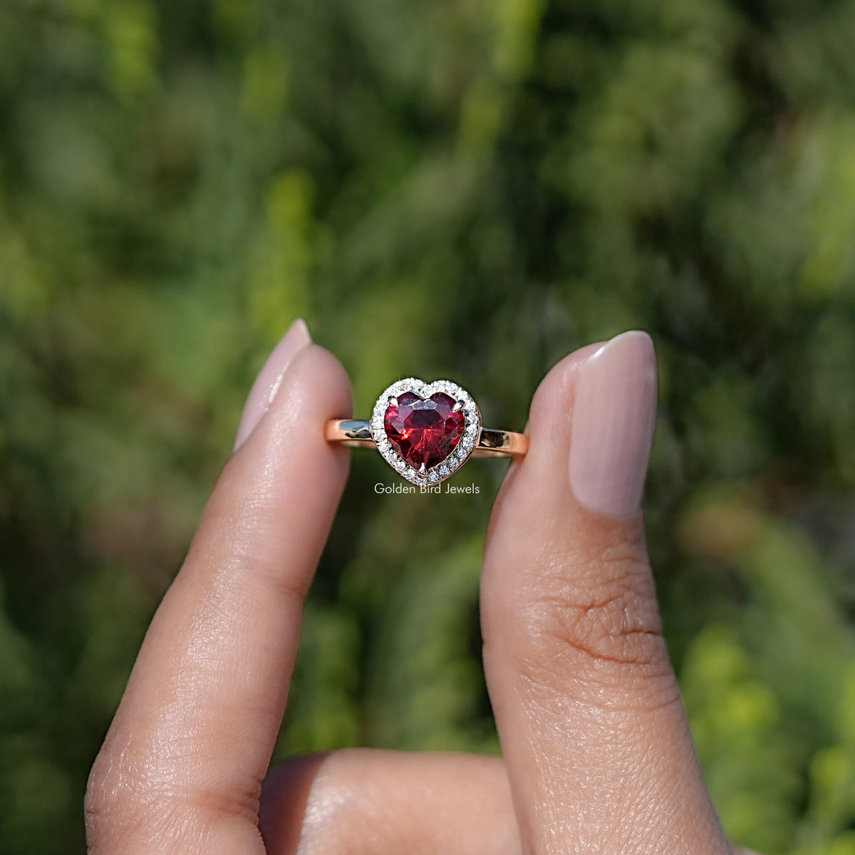 Front view of  Ruby Heart Gemstone engagement ring holding in two fingers 
