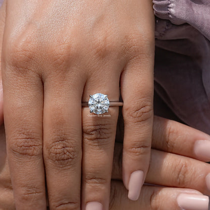 Round solitaire engagement ring worn on finger, round center moissanite with four-prong setting