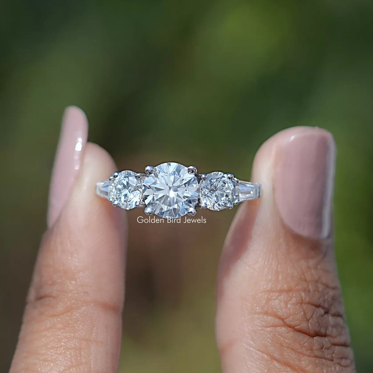 Two fingers holding the Round And Tapered Baguette Cut Five Stone Ring
