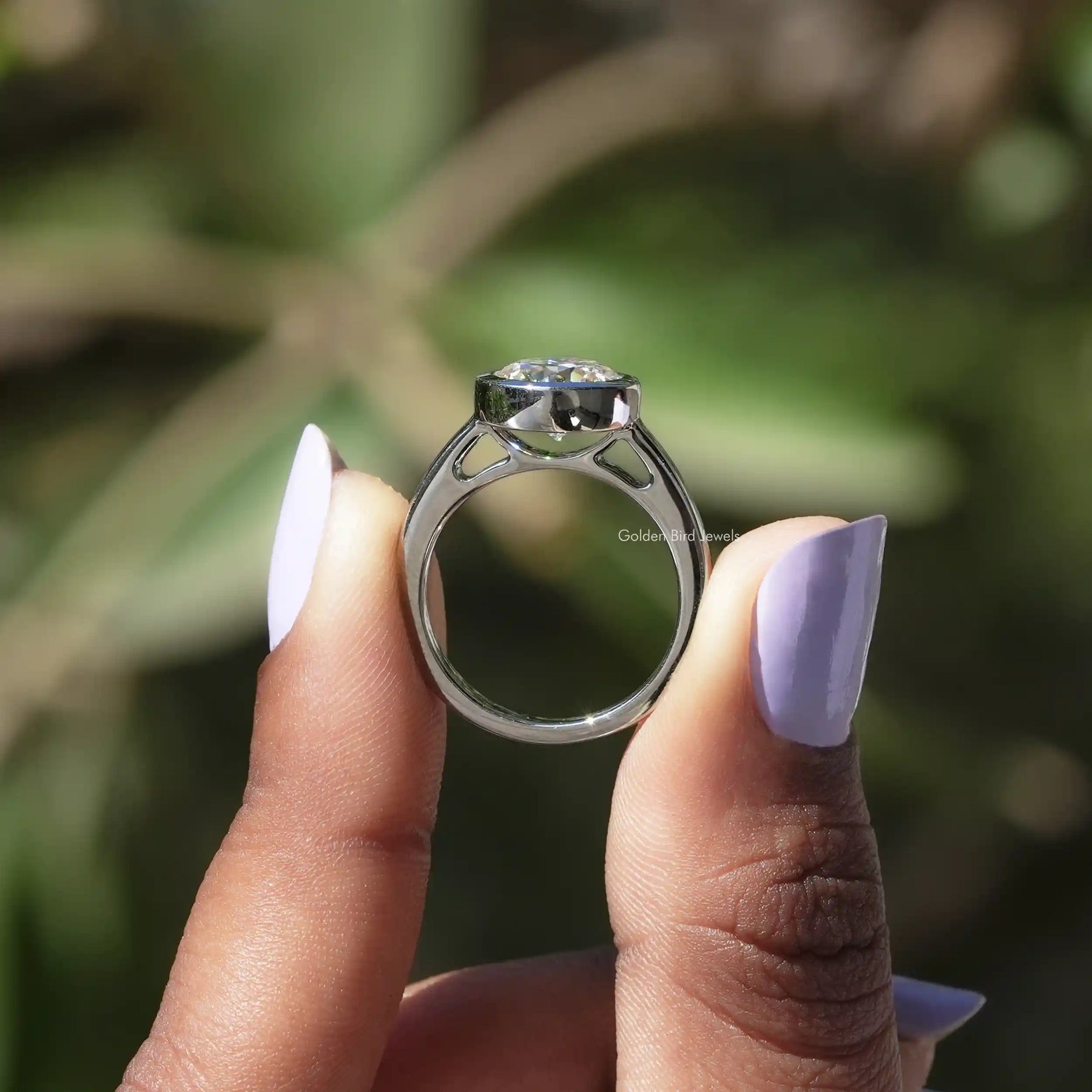 Back View of Round Moissanite Engagement Bezel Set Ring In two fingers