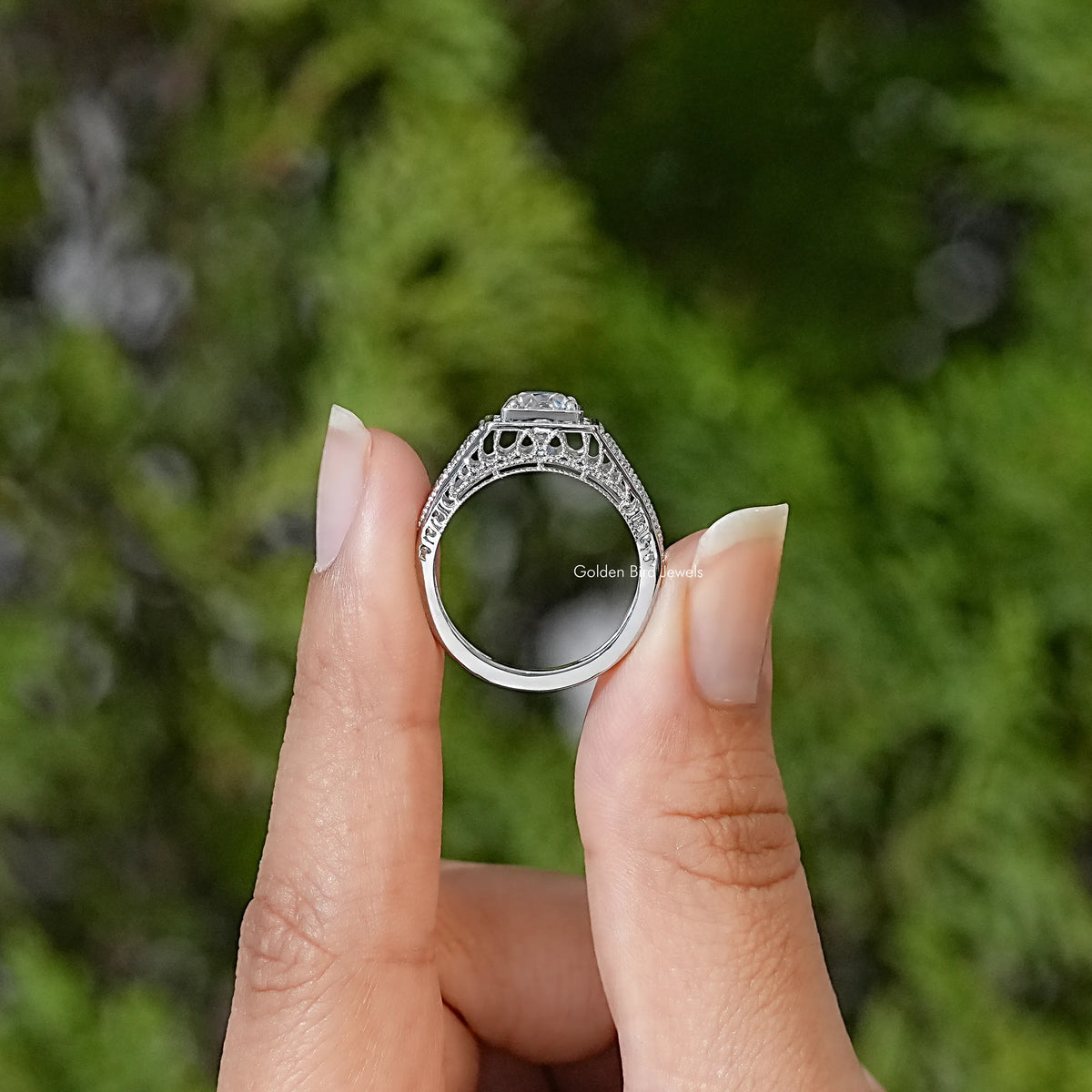 Sterling silver ring viewed from the side, showing openwork shoulders and raised moissanite setting