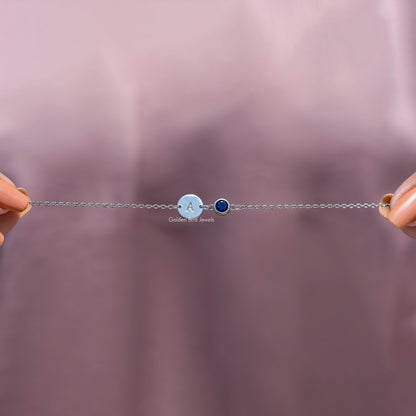 Small sterling silver bracelet with A charm and blue round gemstone, close-up