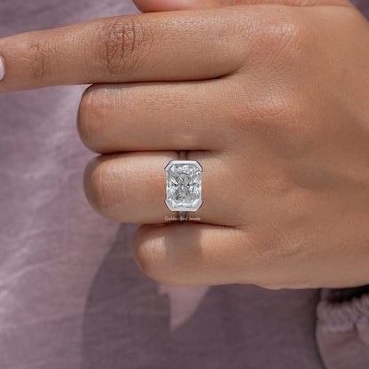 Close-up of radiant-cut center stone set in a silver half-bezel solitaire ring