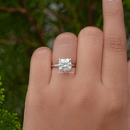 Cushion-cut solitaire engagement ring with silver band and prong-set gemstone on finger