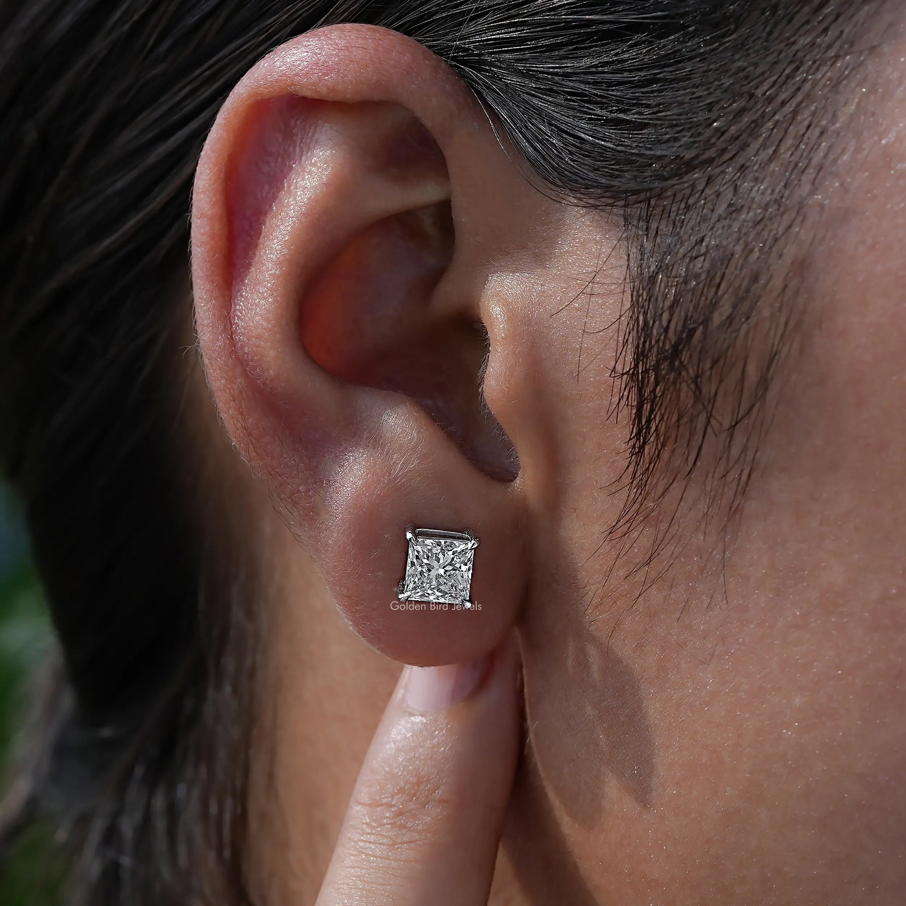 Detailed view of Princess cut diamond stud earrings in secure setting