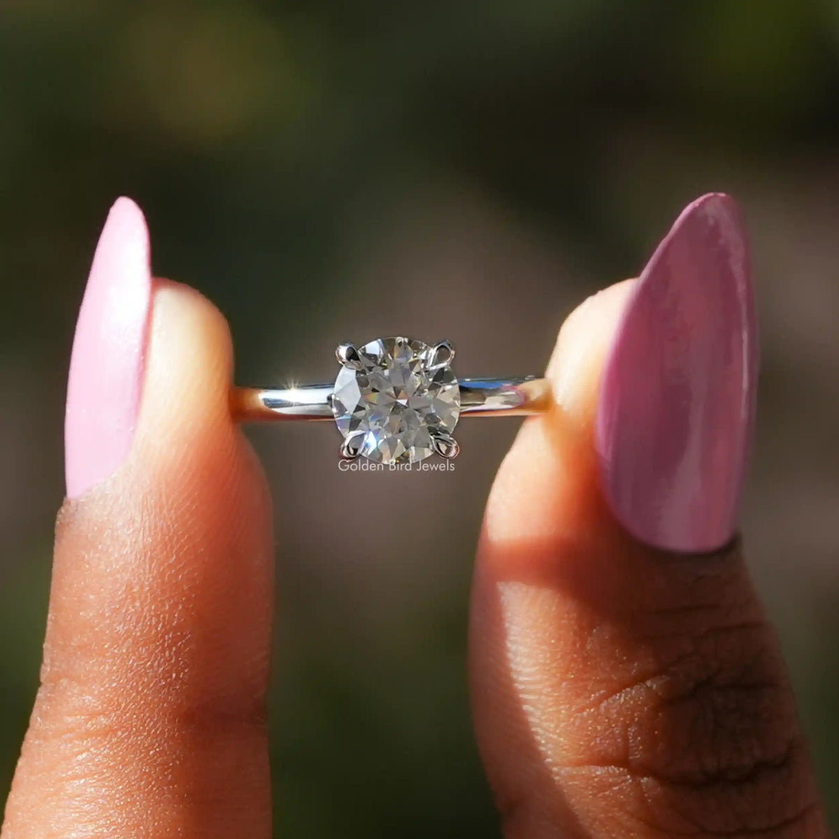Two fingers holding the Round Cut Moissanite Solitaire Ring