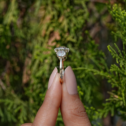 Side View of Cushion Cut Diamond Three Stone Engagement Ring In two fingers