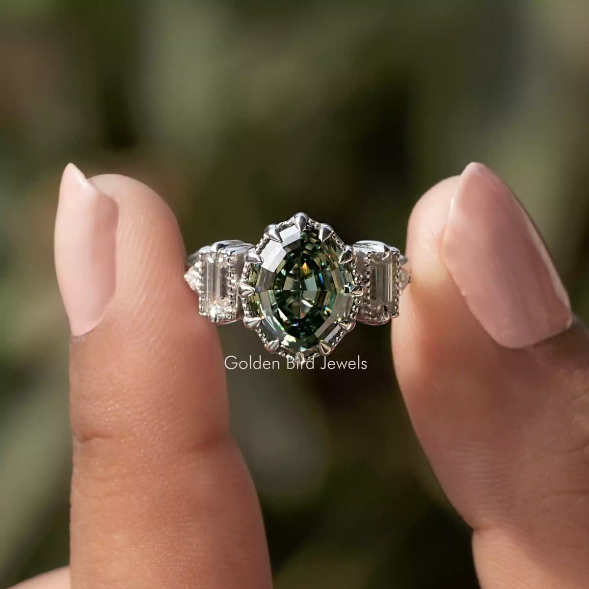 Two fingers holding the Step Cut Oval And Baguette Engagement Ring